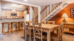 A kitchen with wooden cabinets, a microwave, and a dining area with a wooden table and chairs. - Snowcreek #309  2 Plus Loft, 2 Bathroom Condo Sleeps 8 People with Amazing Mountain Views (Mammoth Lakes)