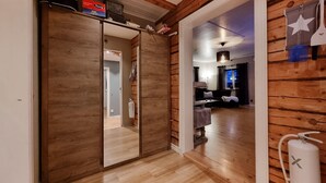 A hallway with wooden walls and flooring, leading to a living area with a sofa and a lamp. - Awesome home in Skepplanda (Skepplanda)