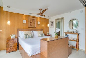Une chambre à coucher moderne avec une tête de lit en bois, un grand lit, un bureau et un ventilateur de plafond.