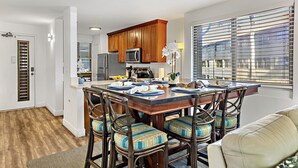 Una cocina moderna con armarios de madera, un refrigerador de acero inoxidable y un comedor con mesa y sillas de madera.