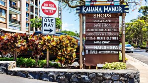 Un letrero de Kahana Manor que muestra una lista de tiendas, incluyendo un pub, restaurante, boutique y más.