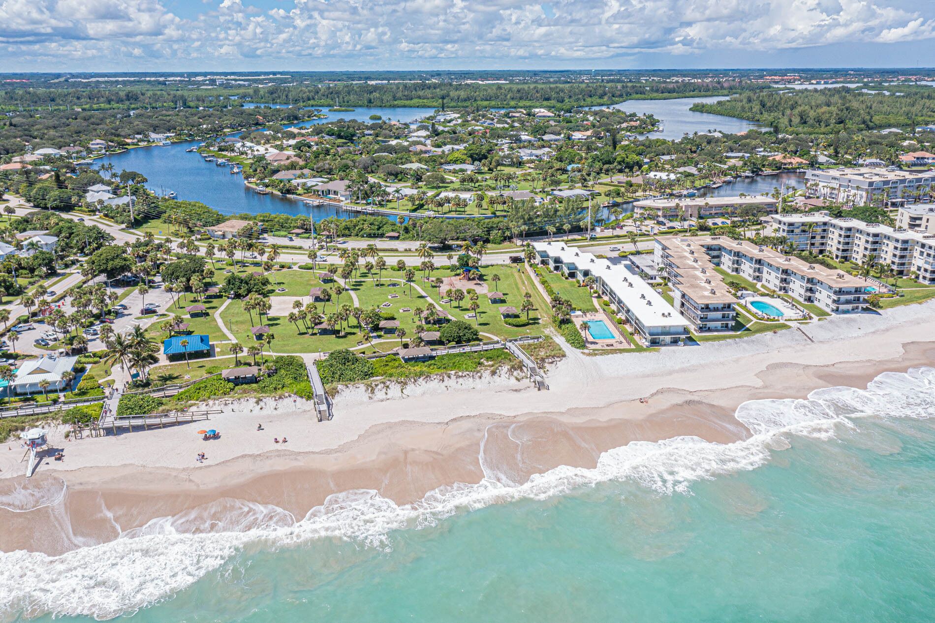 An aerial view of a coastal resort with a beach, a marina, and a large hotel complex.