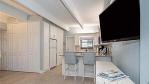 A modern kitchen with white cabinets, a built-in oven, and a large flat-screen TV mounted on the wall. - Ocean front condo,  walk to quaint Vero Beach restaurants and shops.  (Vero Beach)