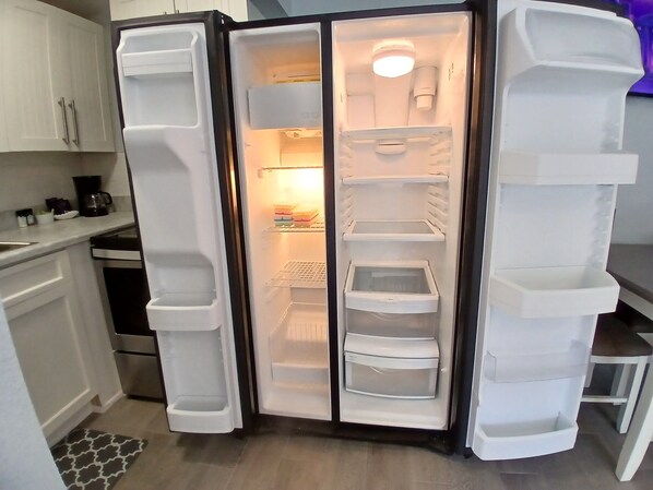 Eine moderne Küche mit einem eingebauten Kühlschrank, einer Kaffeemaschine und einer Mikrowelle auf der Arbeitsfläche.