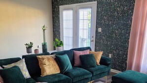 A living room with a dark green sofa, a white coffee table, and a pink throw blanket. - A thoughtfully designed 3-bedroom, 2.5-bath townhome tailored for travelers. (Chambersburg)