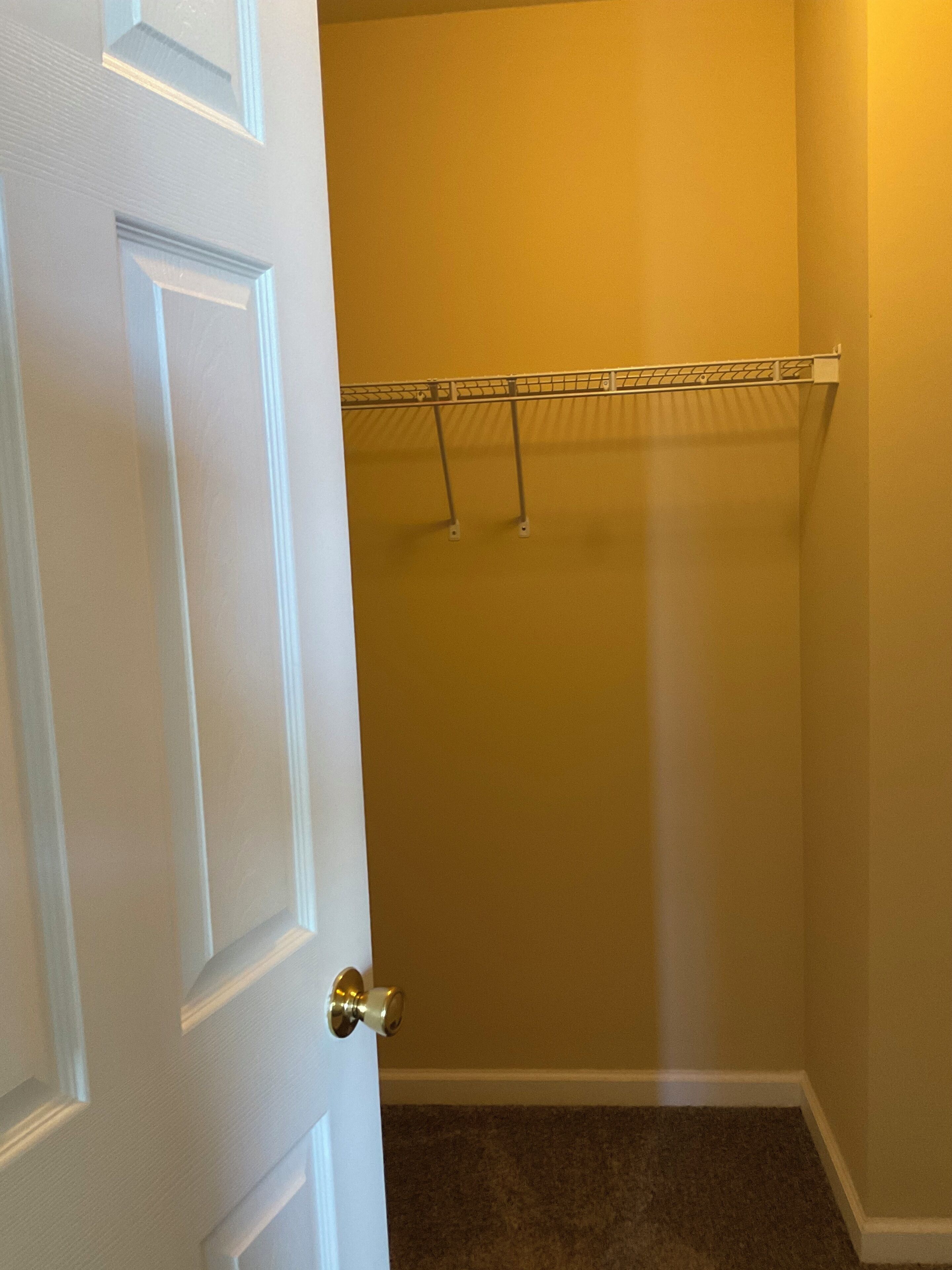A closed door with a white frame, a beige wall, and a metal coat rack with two hooks.