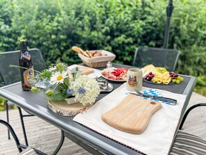 A table set outdoors with a bottle, flowers, cheese, grapes, and a cutting board. - Tiny Haus Prinz Ludwig by Interhome (Riedenburg)