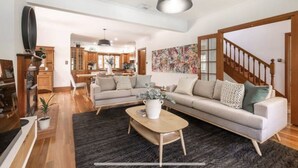 A spacious living room with a large sectional sofa, a coffee table, and a dining area in the background.