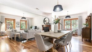 A spacious living room with a wooden dining table, grey sofas, and a fireplace.