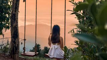 A woman sitting on a swing overlooking a sunset.
