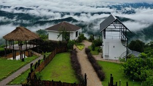 Uma casa de campo com estrutura de colmo e um edifício moderno com painéis solares.