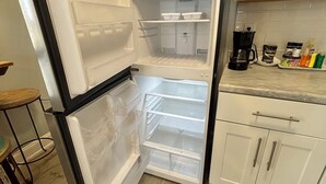 Un refrigerador abierto con varios estantes y una cafetera sobre la encimera.