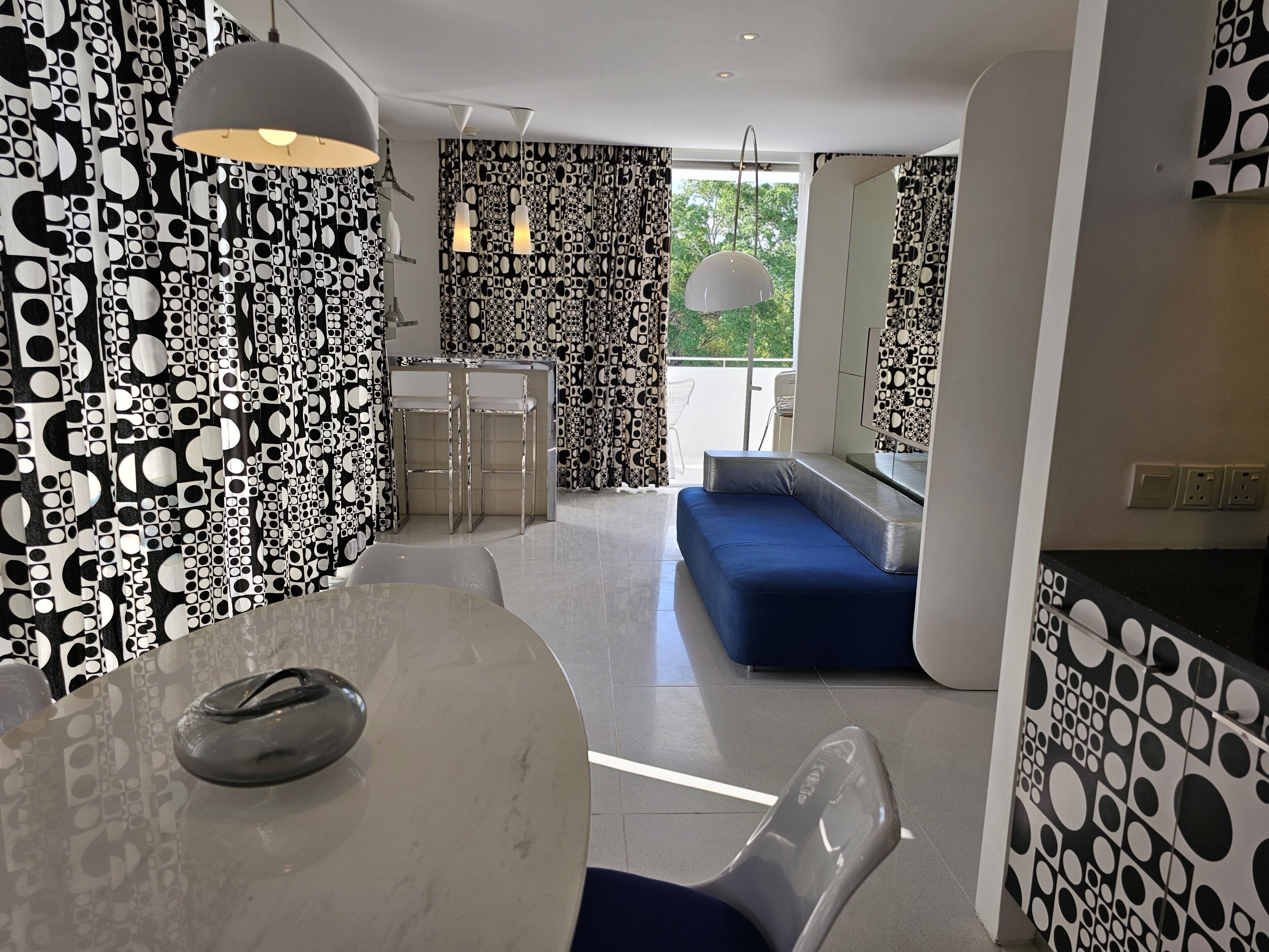 Un intérieur moderne avec un coin repas, un canapé bleu et un mur orné de motifs.