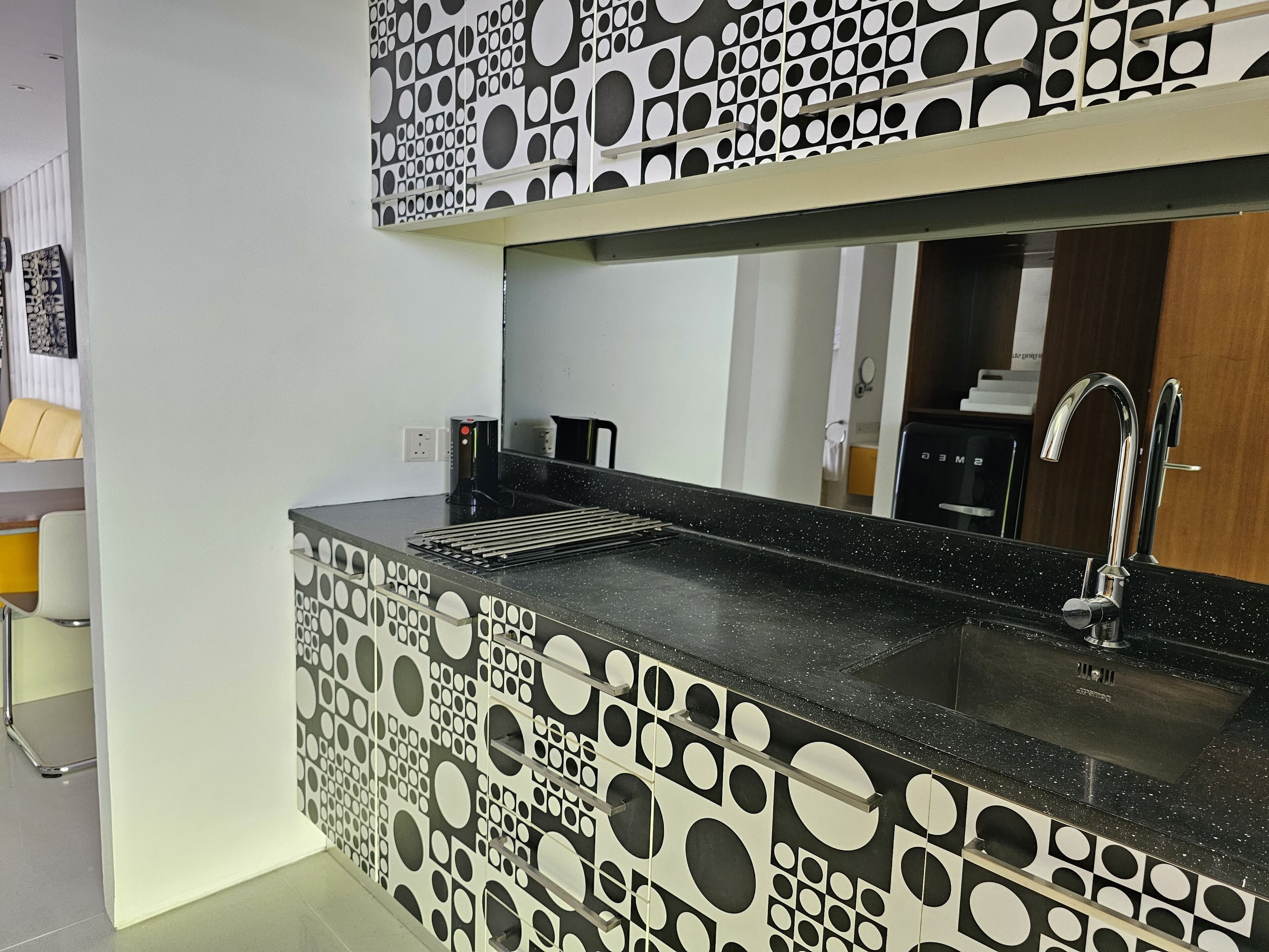 A modern kitchen with a black countertop, a stainless steel sink, and a patterned backsplash.
