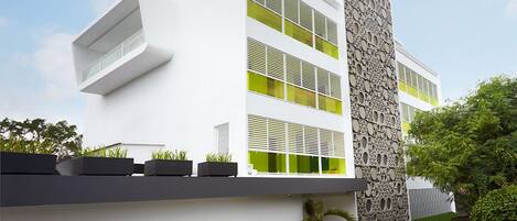 A modern building with a white facade, green-tinted windows, and a textured wall.