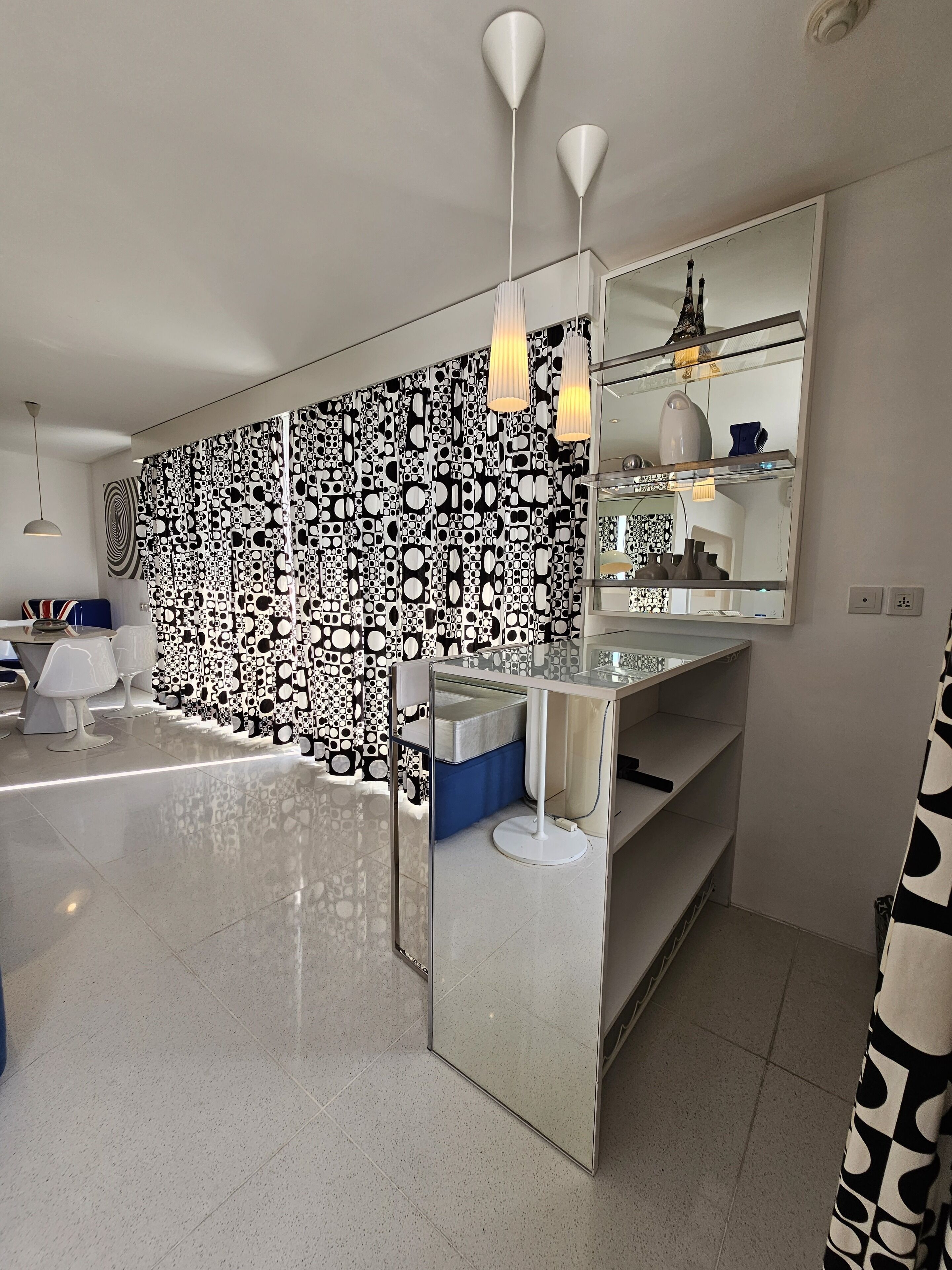 A modern bathroom with a large mirror, white fixtures, and a patterned wall.
