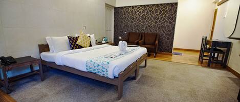 A hotel room with a bed, a chair, a desk, and a small table.