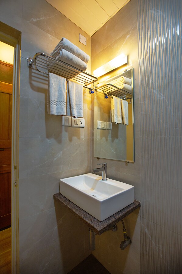 A bathroom with a white sink, towel rack, and mirror. - Hotel Bela Goa (Panaji)