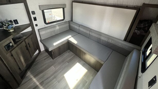 A compact RV interior with a kitchenette, a window, and a seating area. - Cozy RV Getaway for Couples! (Shelby)