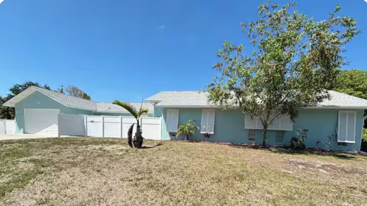 A residential house with a garage, a lawn, and a tree.