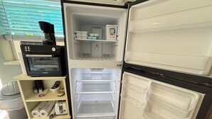 Una cocina equipada con microondas, cafetera y un cubo de basura.