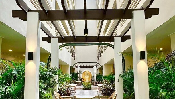A spacious atrium with a central seating area, surrounded by lush greenery and a high ceiling with skylights. - Megaworld Iloilo Condo Unit (Quezon City)