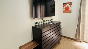 A bathroom with a wooden vanity, a mirror, and a small shelf. - Megaworld Iloilo Condo Unit (Quezon City)
