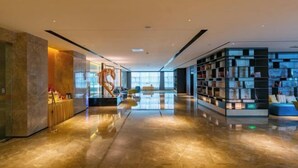 A modern hotel lobby with a marble floor, a central staircase, and a bookshelf filled with books. - Nanning Datang Congyue Hotel (Wuxiang New Area Sports Center) (Nanning)