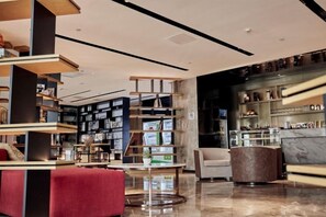 A modern library with multiple bookshelves, a red sofa, and a marble reception desk. - Nanning Datang Congyue Hotel (Wuxiang New Area Sports Center) (Nanning)