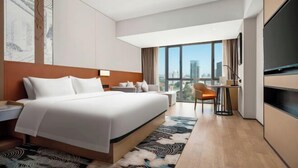 A modern hotel room with a large bed, a desk, a chair, a TV, and a view of the city. - Nanning Datang Congyue Hotel (Wuxiang New Area Sports Center) (Nanning)