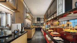 A modern hotel kitchen with a buffet setup, featuring a marble floor, wooden cabinets, and various food items displayed on the counter. - Nanning Datang Congyue Hotel (Wuxiang New Area Sports Center) (Nanning)