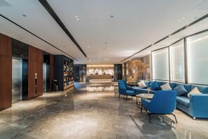 Un hall d’entrée moderne avec un comptoir d’accueil, un espace salon et une grande fenêtre.