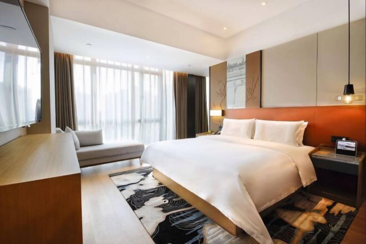 A hotel room with a bed, a sofa, a desk, and a TV.