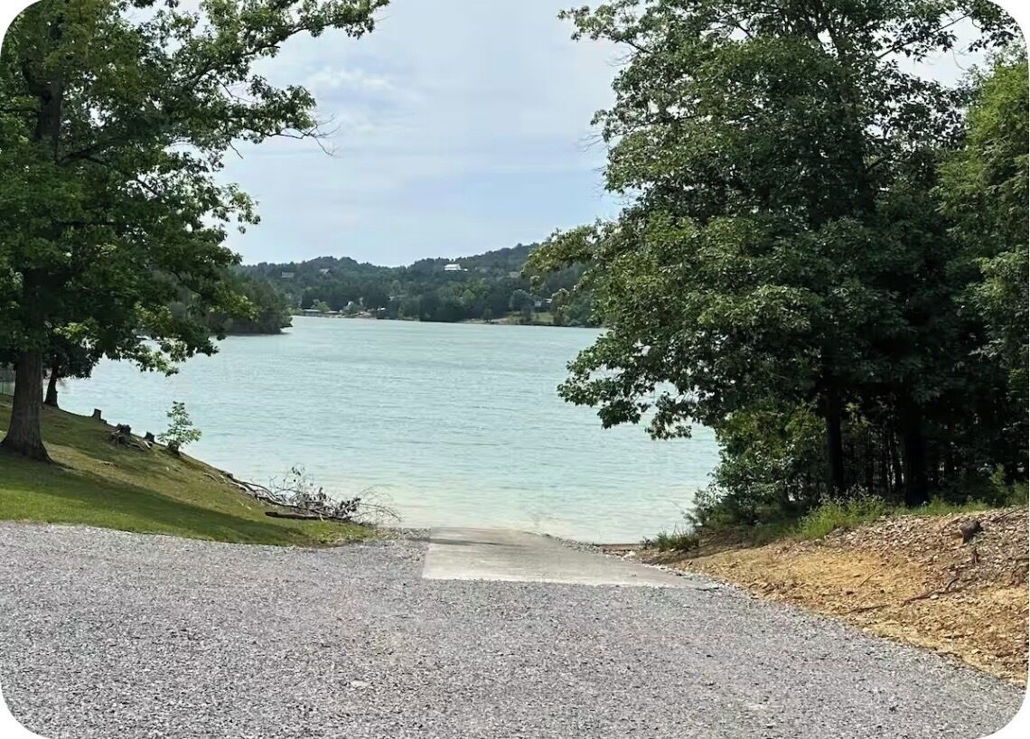 Un sendero de grava que lleva a un lago rodeado de árboles.