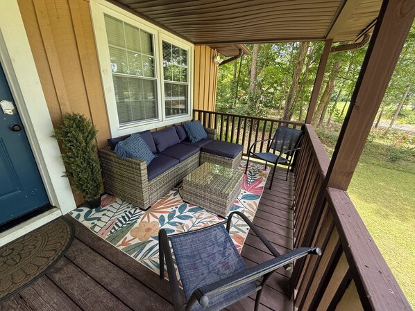 A covered porch with a wicker sofa, two chairs, and a small table.