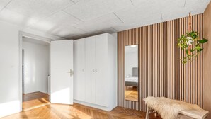 A modern room with a herringbone wooden floor, white wardrobes, a mirror, and a bench with a fur throw. - "Ullakarin" - 200m from the sea by Interhome (Thyborøn)
