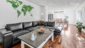 A modern living room with a leather sofa, a coffee table, and a world map on the wall. - "Ullakarin" - 200m from the sea by Interhome (Thyborøn)