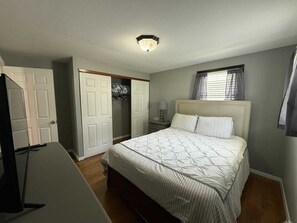 A bedroom with a bed, a wardrobe, a desk, and a ceiling light.