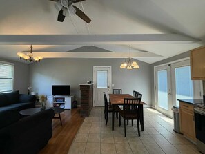 A spacious living area with a sofa, TV, dining table, and chairs.