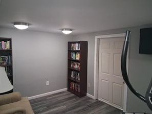 A room with a bookshelf, a door, and a lamp.