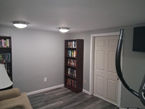 A room with a bookshelf, a door, and a lamp.
