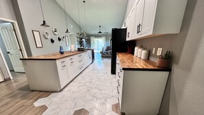 A modern kitchen with a central island, white cabinetry, and a hexagonal patterned rug. - Modern Glendale Getaway /Mins from I-17 & 101 / 6 Flags, Hiking & Golf close by (Glendale)