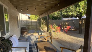 A covered patio with outdoor furniture, a swing set, and a view of the backyard. - Modern Glendale Getaway /Mins from I-17 & 101 / 6 Flags, Hiking & Golf close by (Glendale)