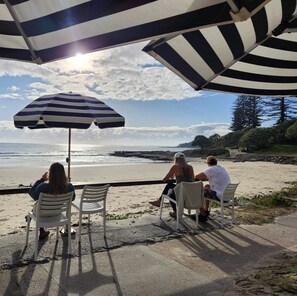 A beachside seating area with striped umbrellas and chairs overlooking the ocean.