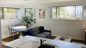 Cocina compacta con lavamanos, mesa de comedor y sofá gris.
