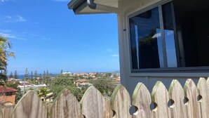 Vista desde una ventana con vista a una zona costera con casas y árboles.