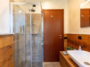 A modern bathroom with a glass-enclosed shower, wooden vanity, and a large sink.
