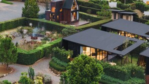 Una casa moderna con una amplia terraza, rodeada de jardines cuidados y un camino de acceso.