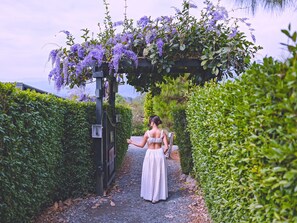 A pathway leading to a gate with a woman in a white dress.