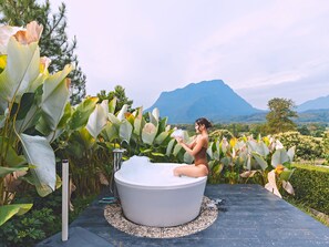 A woman in a bathtub outdoors with a mountain view. - THE CAMPIAN (Chiang Dao)